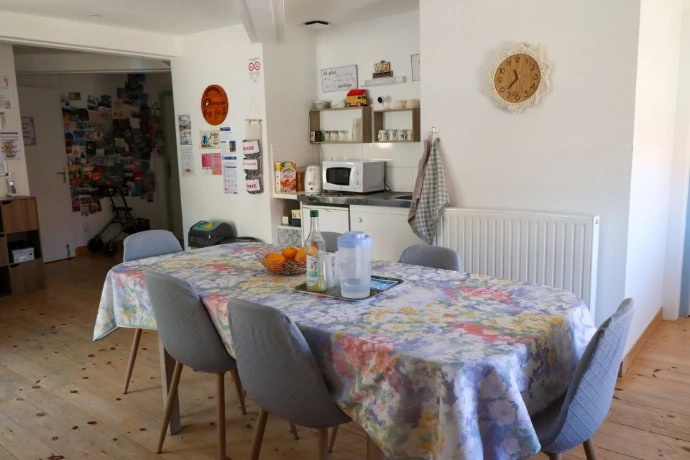 Salle à manger de la Maison Chaumet avec une grande table, des chaises et un espace de vie ouvert sur la cuisine.