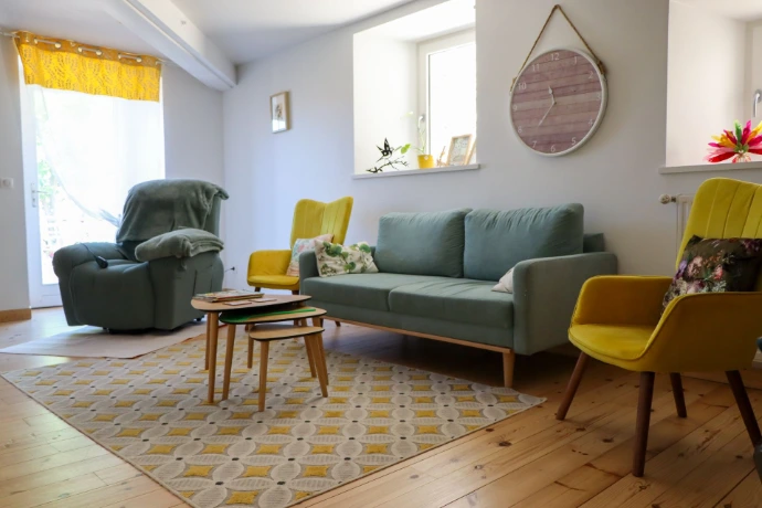 Salon convivial de la Maison Chaumet avec canapé, fauteuils, table basse et décoration chaleureuse.