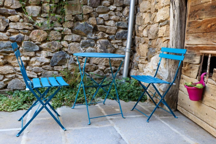 Petit espace extérieur aménagé avec une table et des chaises, entouré de murs en pierre.
